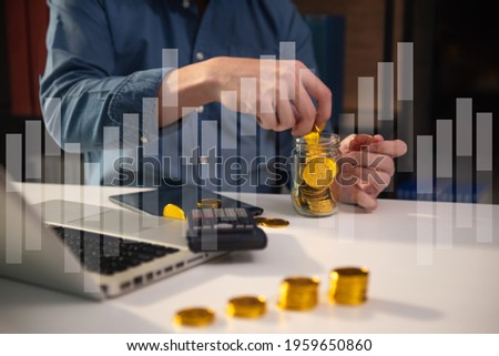 Businessman holding coins putting in glass with using  calculator to calculate concept saving money for finance accounting at home office.