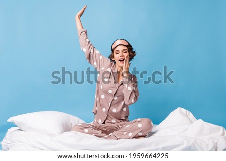 Full body photo of sleepy woman yawn raise hand sit blanket wear sleepwear isolated on blue color background Royalty-Free Stock Photo #1959664225