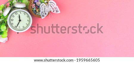 Spring and feminine workspace background, pink office desk with flowers and alarm clock, flat lat and top view, copy space photo