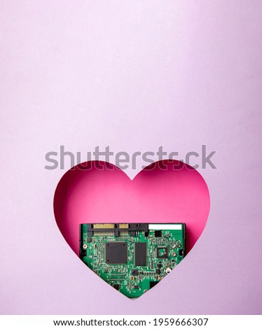 The green printed circuit board with microprocessors is located in a pink heart-shaped cavity. All around is purple. Copy Space. Love. Technology. Artificial intelligence. Robotics. Royalty-Free Stock Photo #1959666307