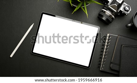 Dark creative workspace with digital tablet, camera, stationery and stylus pen, top view, clipping path