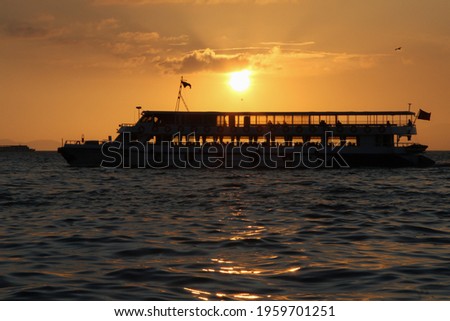 Silhouettes of turkish steamboat in İzmir with seagulls at golden sunset. Sunset in İzmir Kordon