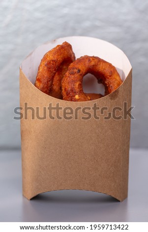 onion rings in a cardboard bag on a gray background.