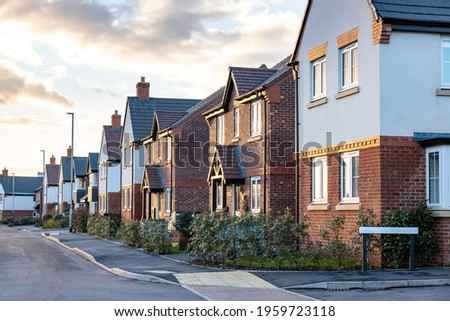 Houses in England with typical red bricks at sunset - Main street in a new estate with typical British houses on the side - Real estate and buildings concepts in UK Royalty-Free Stock Photo #1959723118