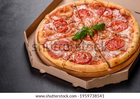 Tasty fresh oven pizza with tomatoes and cheese on a dark concrete background
