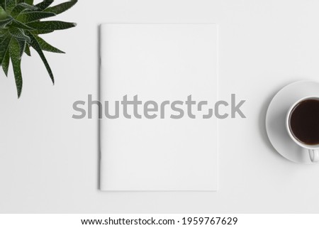 Magazine mockup with a cup of coffee and a aloe vera plant on the white table. Royalty-Free Stock Photo #1959767629