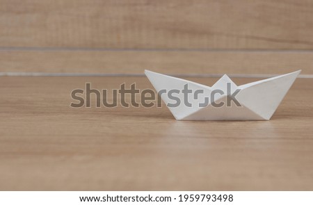 origami sailboat on wood background. symbolic for business, conceptual, and 