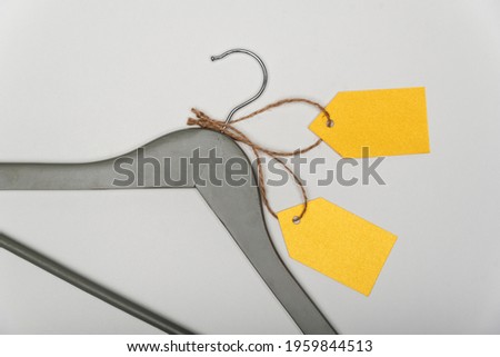 Grey coat hanger with yellow paper labels on white background. Blank label , mockup template. Clothing tag.