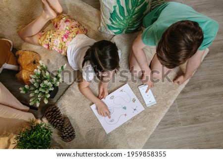 Top view of unrecognizable children playing treasure hunt at home on the carpet Royalty-Free Stock Photo #1959858355