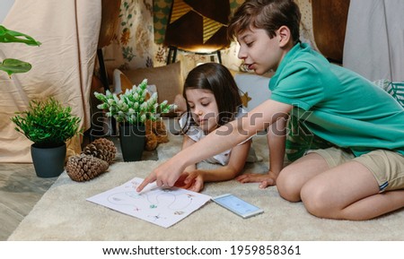 Children playing treasure hunting game in a diy tent at home. Home vacation concept Royalty-Free Stock Photo #1959858361