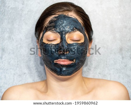 Woman relaxing with charcoal facial mask.