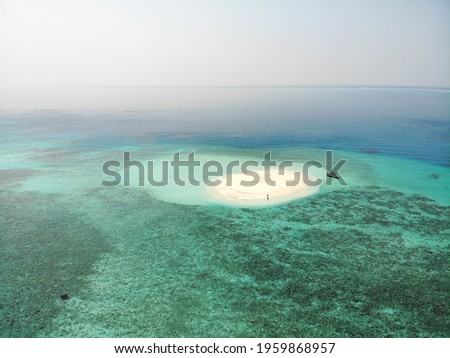 Drone photo of couple standing on breathtaking sandbank with fine sand and turquoise water. Aerial picture of guy on tropical beach, Maldives, Indian Ocean.
