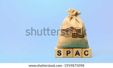 Wooden blocks with the word SPAC and money bag - Special purpose acquisition company. Simplified listing of company, merger bypassing stock exchange IPO. Assessment of benefits and risks of investment