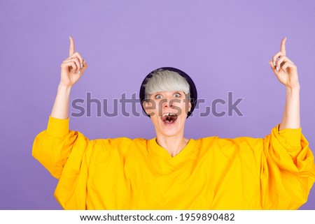 Stylish european woman on purple background pointing up with fingers showing advertisement, surprised face and open mouth