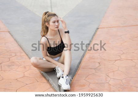 The running girl sit-down on ground for relax muscle after she jogging in morning , she acting and post for take photo relax on time