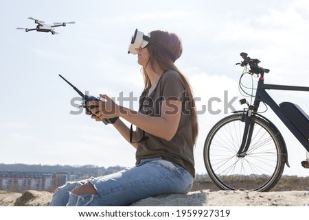 young woman flying a drone with remote controller and virtual reality goggles 