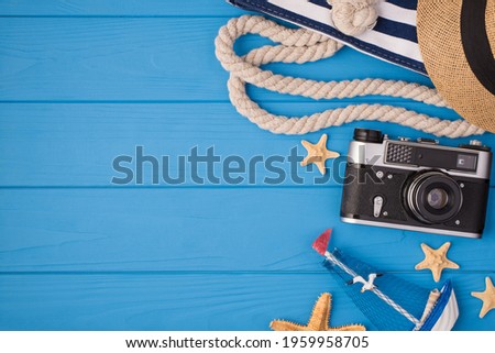 Above photo of bag sunhat camera starfish and ship isolated on the blue wooden background with copyspace