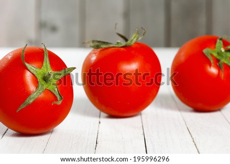 three tomatoes on bright wood 