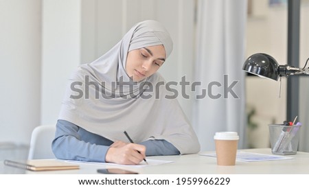 Pensive Young Arab Woman Writing on Paper 