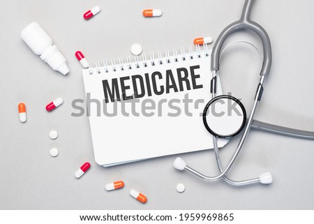 In the notebook is the text medicare next to a stethoscope, pills and glasses.