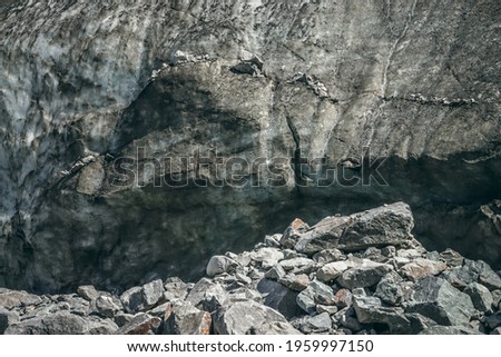 Nature background with icefall near glacier with cracks and scratches. Natural backdrop with icy wall and moraines. Beautiful landscape with shiny glacial wall and stones in sunlight. Glacier texture.