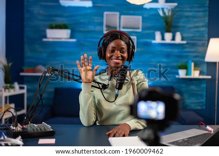 African blogger waving at audience while filming podcast. On-air production internet broadcast host streaming live content, recording digital social media