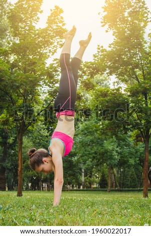 European girl in a light tracksuit doing yoga in the park in the afternoon in the summer. Gymnastics in nature. Thin woman outdoor.