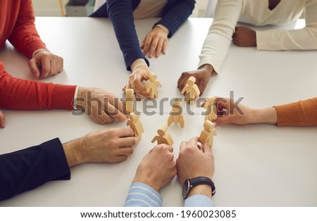 Diverse business team members join wooden human figures around space rocket on table in corporate meeting. Metaphor for teamwork. Symbol of developing new group projects and launching new products Royalty-Free Stock Photo #1960023085