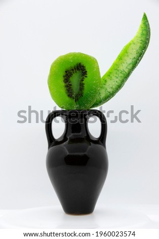Bright green candied kiwi fruit with seeds and pomelo in a brown jug with handles. Dried fruits.