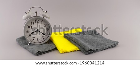 Color trends themed still life with alarm clock placed near two tone grey and yellow textile