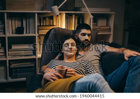 couple relaxing at home. they have cosmetic clay face mask applied on face