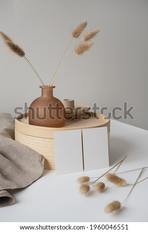 Blank paper cards with mockup copy space, bunny tail grass, wooden tray, neutral beige blanket. Aesthetic minimal business template on white wall. Background for blog, web, social media