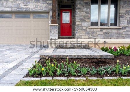 Luxury landscaping of paver driveway, landing, and steps with matching pattern detail and front garden. Royalty-Free Stock Photo #1960054303