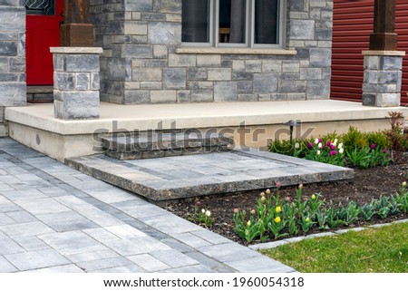 Luxury landscaping with precast paver driveway, landing and steps with matching pattern detail and front garden. Royalty-Free Stock Photo #1960054318