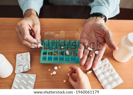 Senior man organizing his medication into pill dispenser. Senior man taking pills from box. Healthcare and old age concept with medicines. Medicaments on table Royalty-Free Stock Photo #1960061179