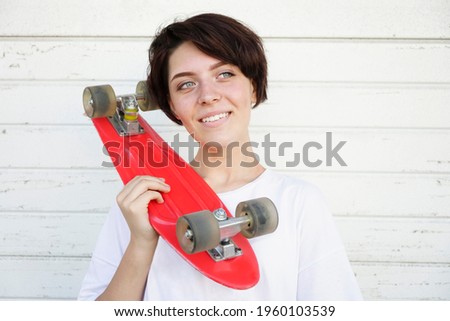Young woman holding red skateboard on shoulder isolated on  white wall background