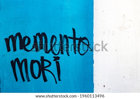 Latin phrase Memento mori (Remember death) in black letters on blue background