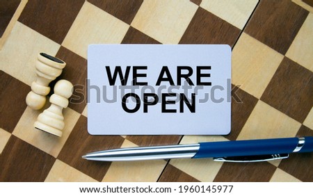 Business card with text We Are Open on a chess board with pen and eyeglasses. Concept photo