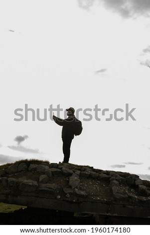 An adult hiker with a backpack taking a picture of the scenery with a phone in Spain