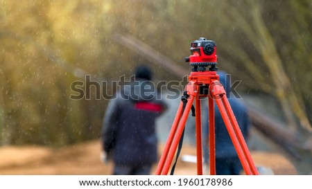 optical level on a rainy day against the background of standing people at a shallow depth of field