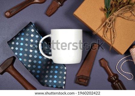 Father's Day or masculine birthday theme white coffee cup flatlay styled with gift, chocolate tool set and tie. White product mock up with negative copy space for your text or design here.