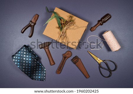 Father's Day or masculine birthday theme flatlay background styled with gift, chocolate tool set and tie. Blog hero header creative composition.