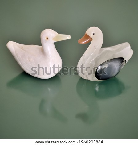 Photography of two onix statue of two ducks on a green background