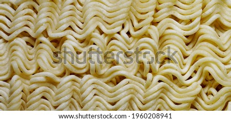 Instant noodles.
Close up of raw dried noodles.
Uncooked noodles texture.
Precooked dehydrate noodle blocks. 
Asian food. Food background.
Full depth of field. Panoramic image. Hi-res banner.
