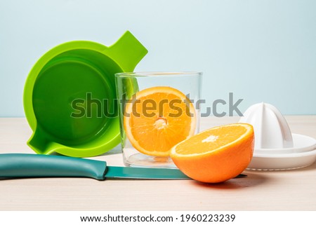 A closeup shot of freshly cut oranges in a glass next to a juicer