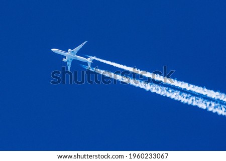 Sharp telephoto close-up of jet plane aircraft with contrails cruising from Tokyo to Chicago, altitude AGL 35,000 feet, ground speed 472 knots. Royalty-Free Stock Photo #1960233067