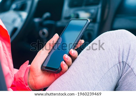The girl in the car holds a mock-up of a smartphone with a white screen. Mockup technology