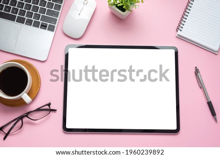 Mock up. Digital tablet blank white screen on the desk pink background.