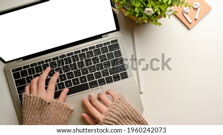 Top view of female hands typing on laptop keyboard on white table decorated with plant pot, clipping path