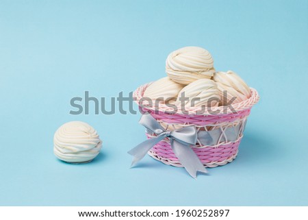 Wicker basket with vanilla meringue on a blue background. Delicious sweetness of eggs and sugar.